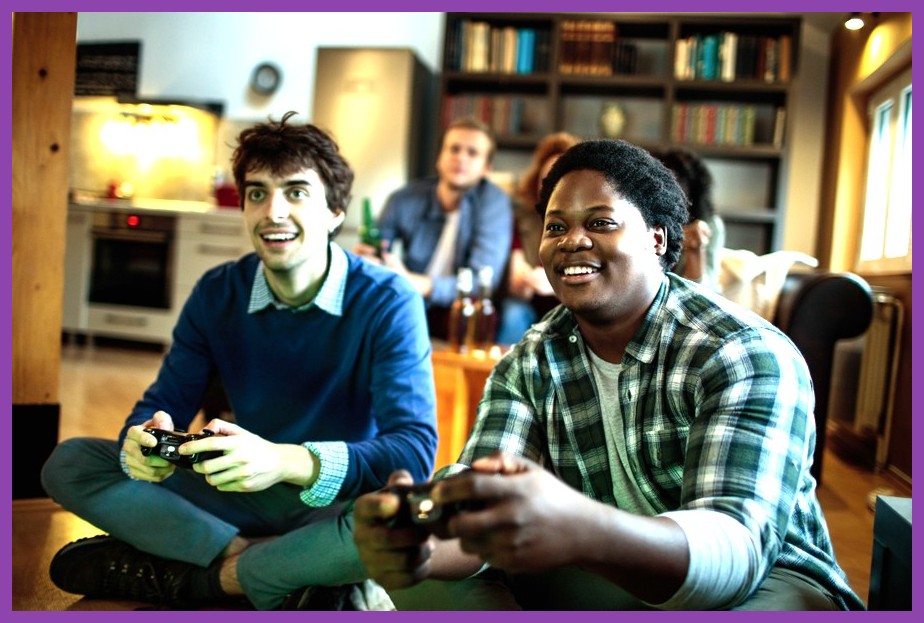 Two friends playing a co-op split-screen game using gamepads in front of a screen